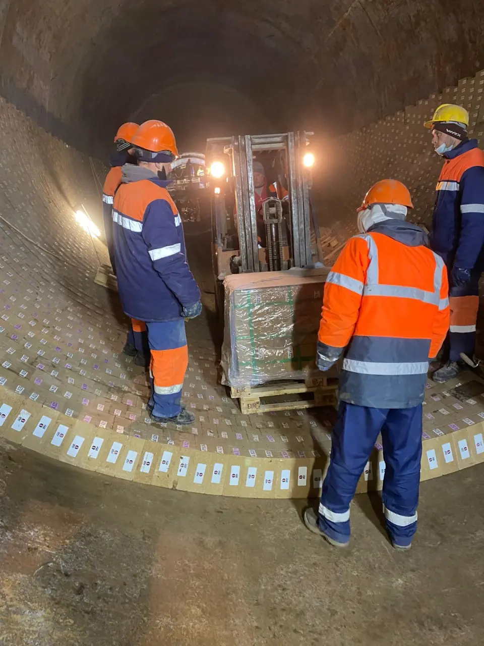 Site team and palletised materials inside a large lined vessel