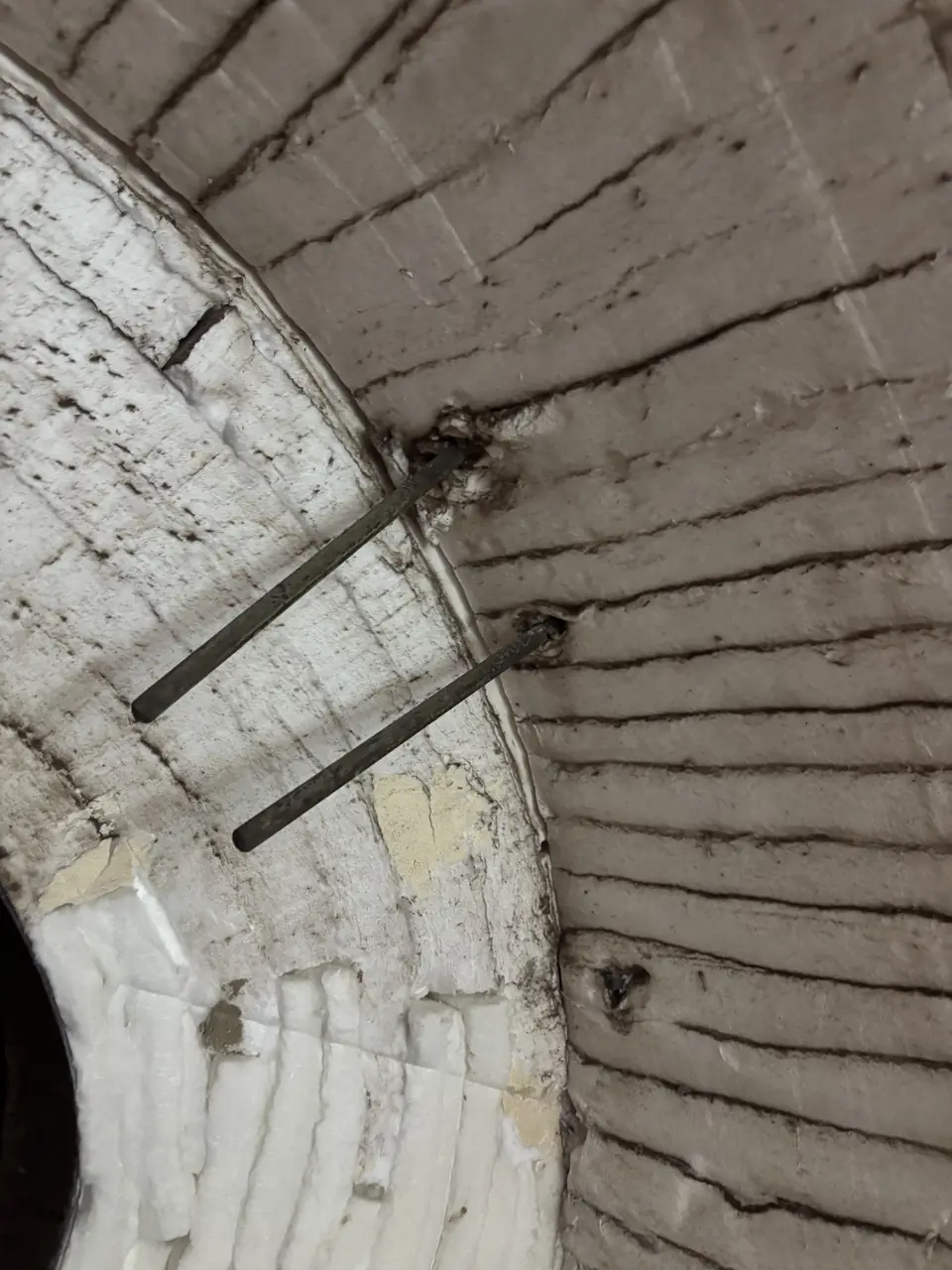 Edge of the retained ceramic-fibre lining during strip-out, with exposed anchors